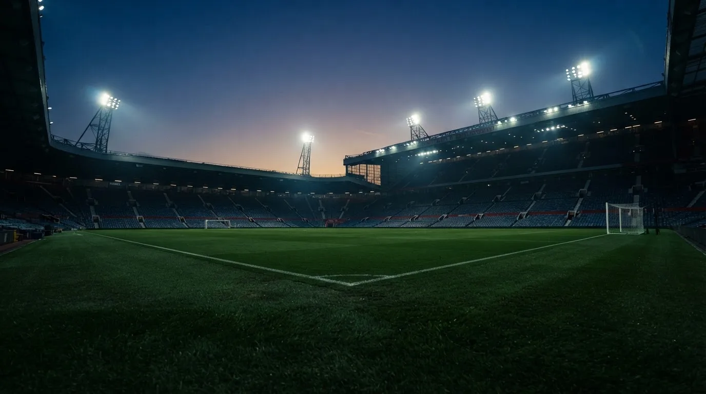 An empty football stadium with floodlight masts at dusk