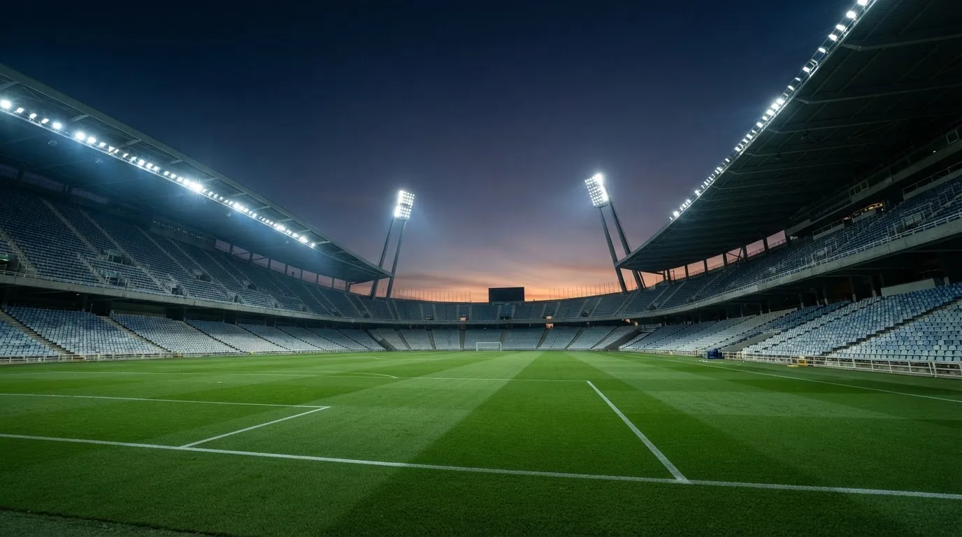 An empty football stadium with floodlight masts at dusk