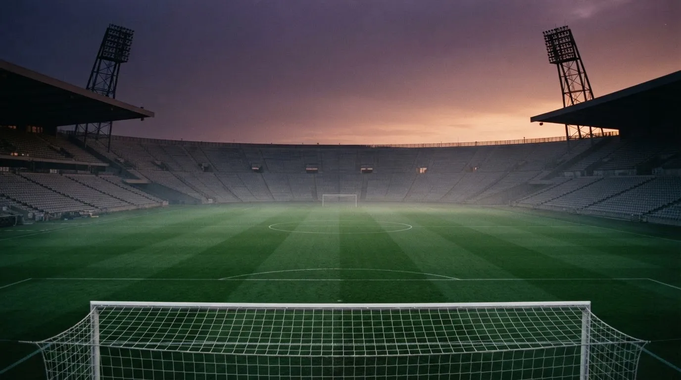 An empty football stadium with floodlight masts at dusk