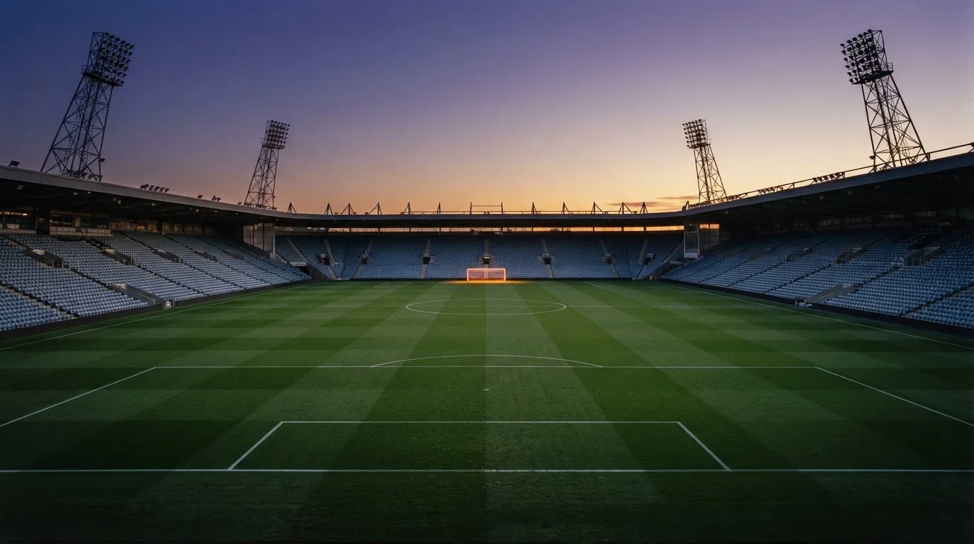 An empty football stadium with floodlight masts at dusk