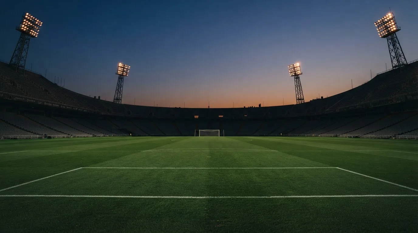 An empty football stadium with floodlight masts at dusk