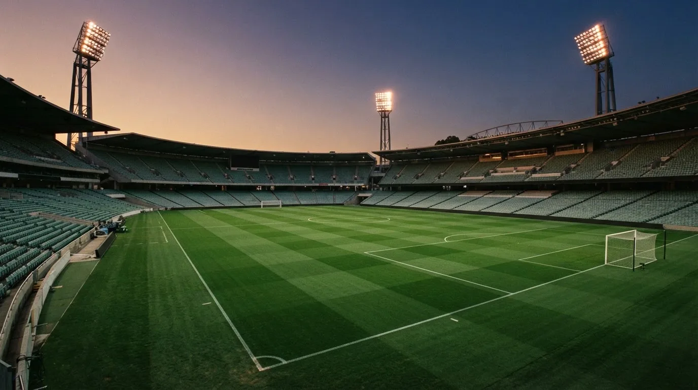 An empty football stadium with floodlight masts at dusk