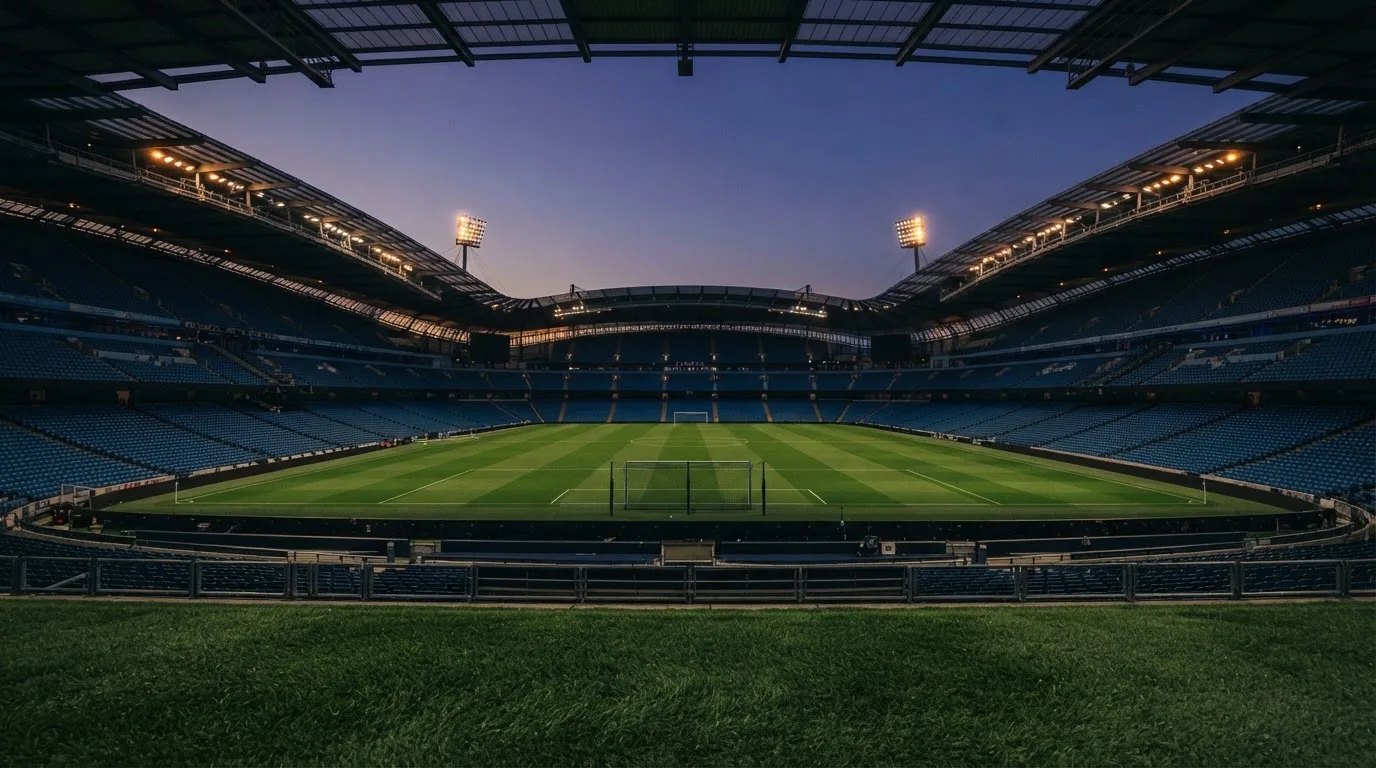 An empty football stadium with floodlight masts at dusk