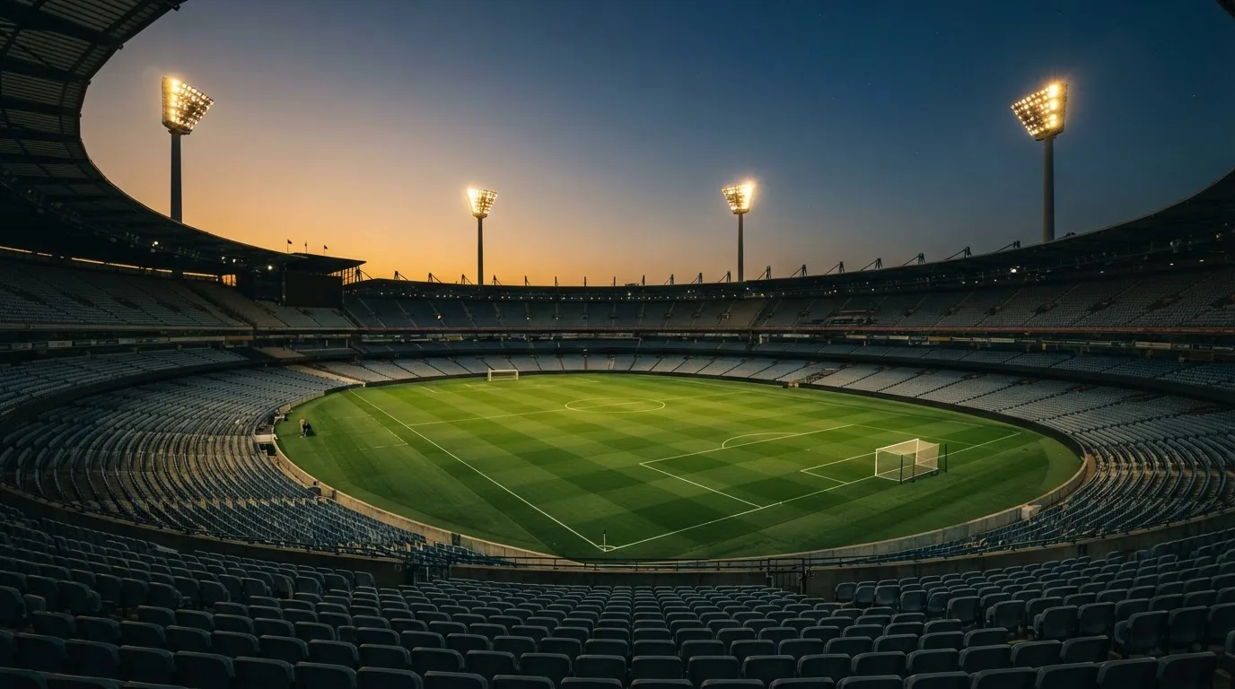 An empty football stadium with floodlight masts at dusk