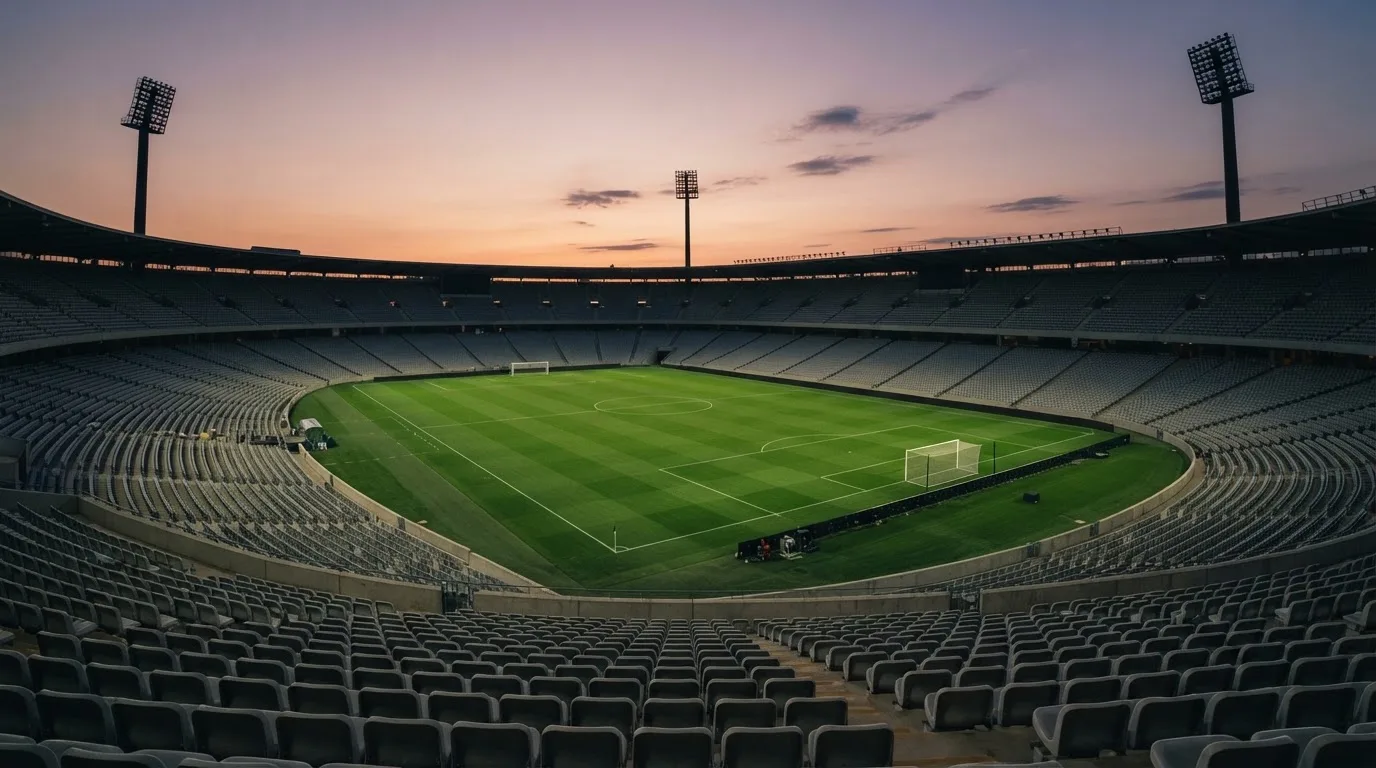 An empty football stadium with floodlight masts at dusk