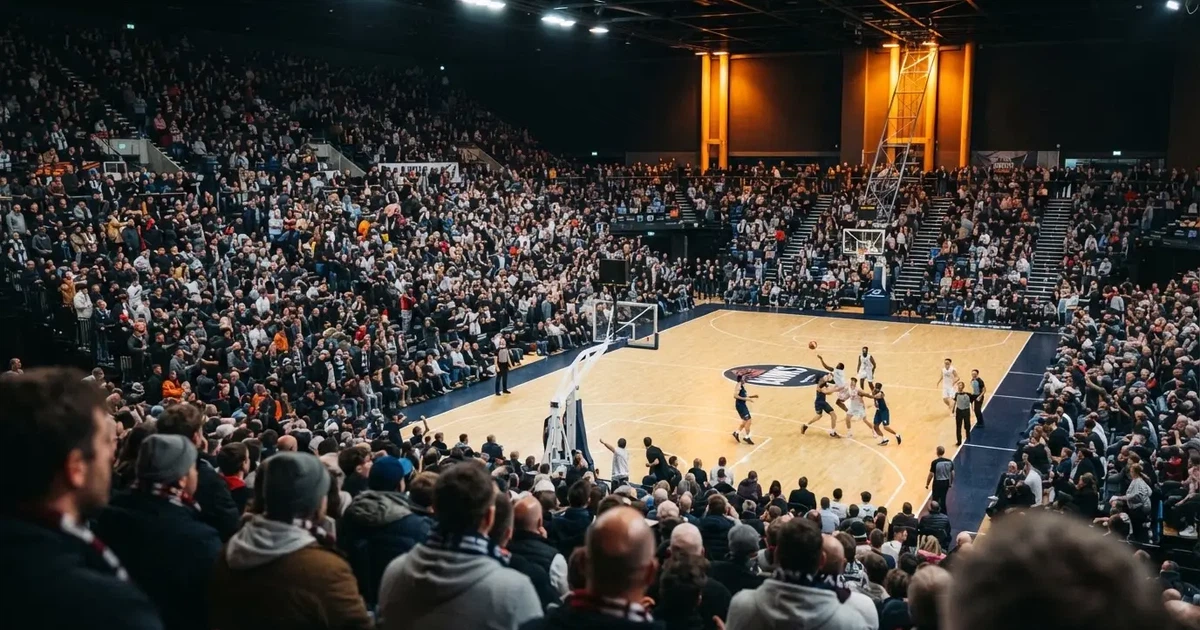 A packed sports hall under floodlights photographed from a long way off