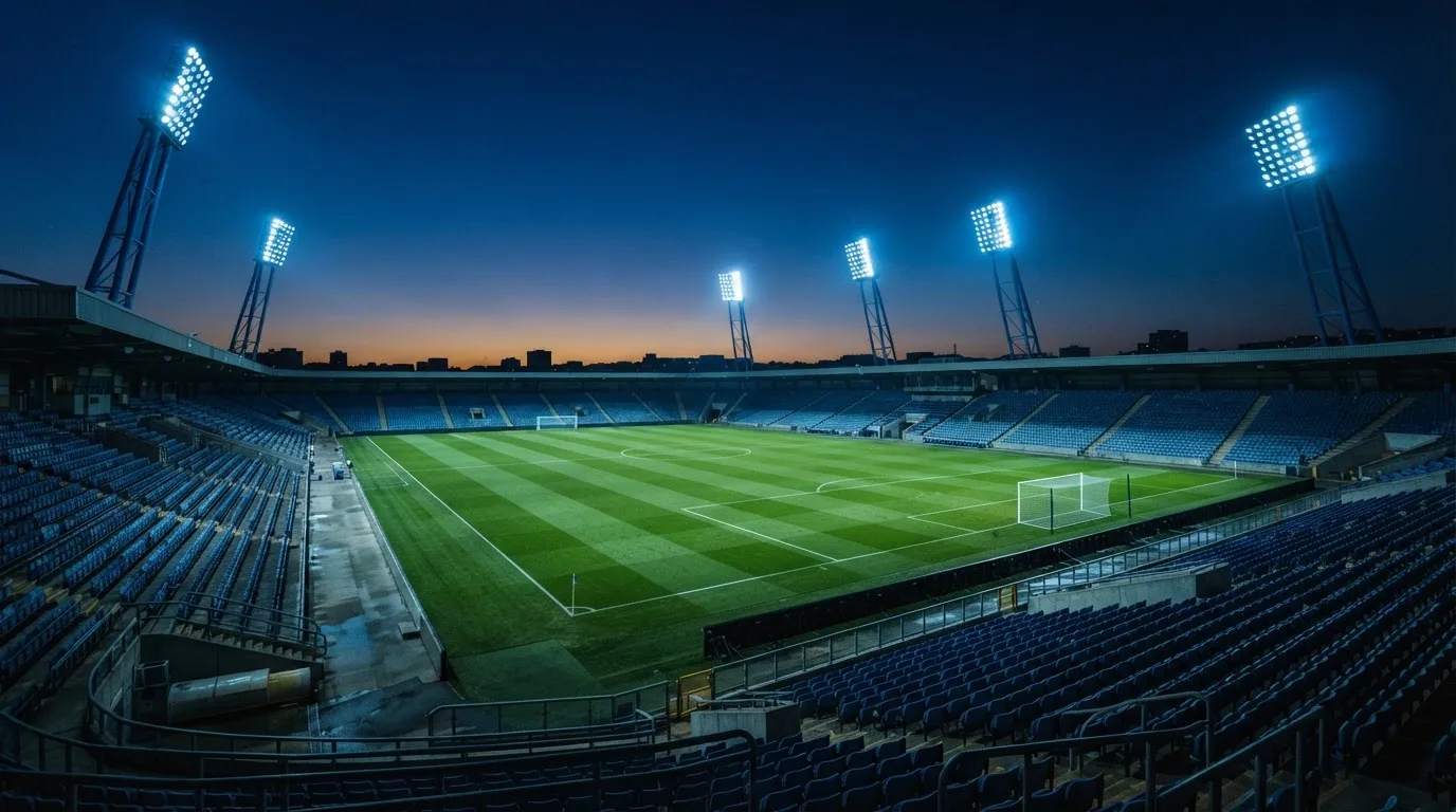 An empty football stadium with floodlight masts at dusk