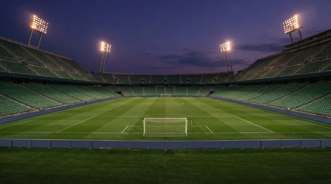 An empty football stadium with floodlight masts at dusk