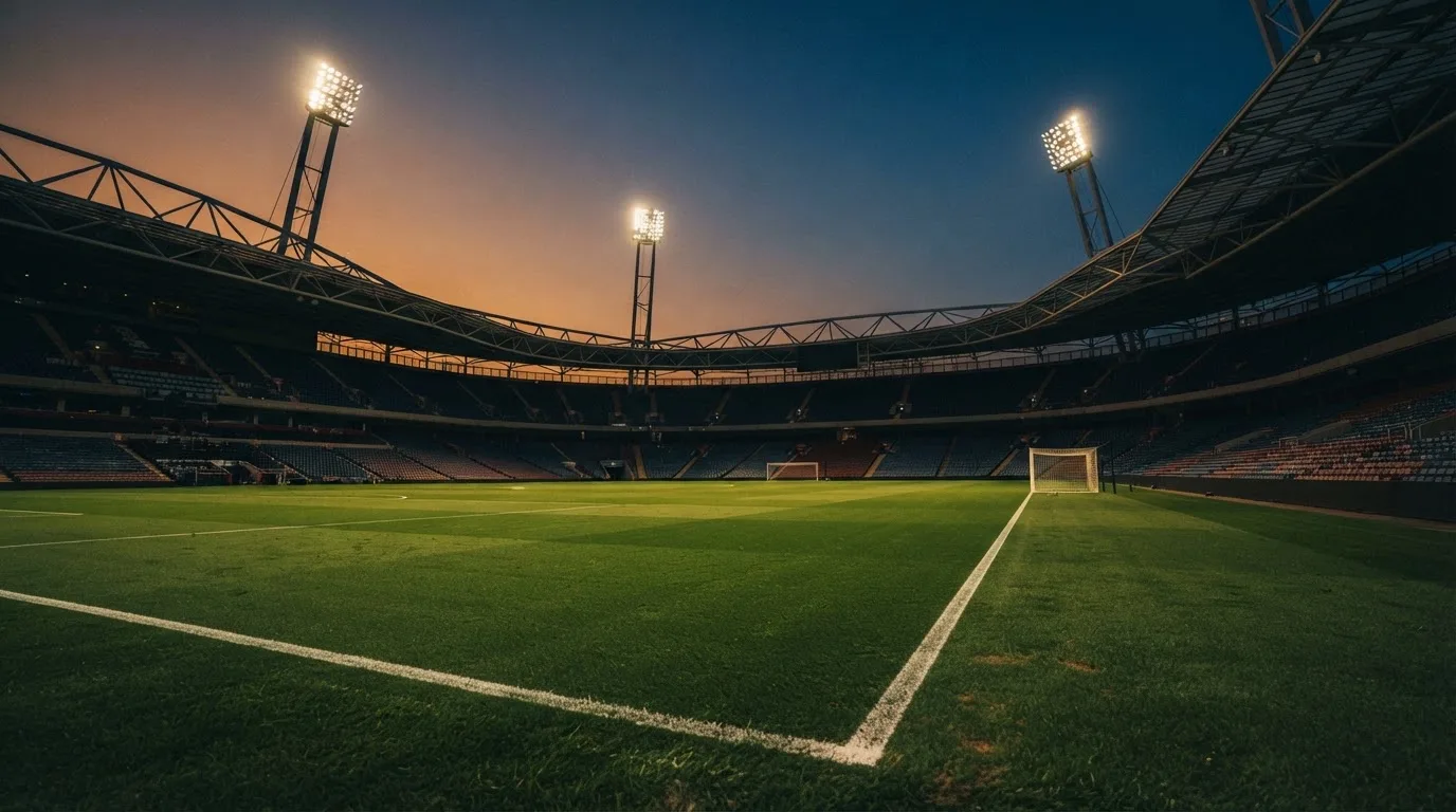 An empty football stadium with floodlight masts at dusk