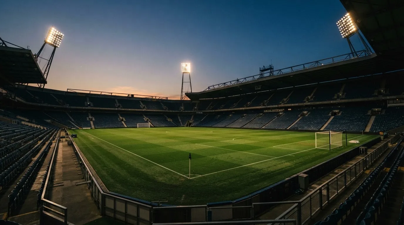 An empty football stadium with floodlight masts at dusk
