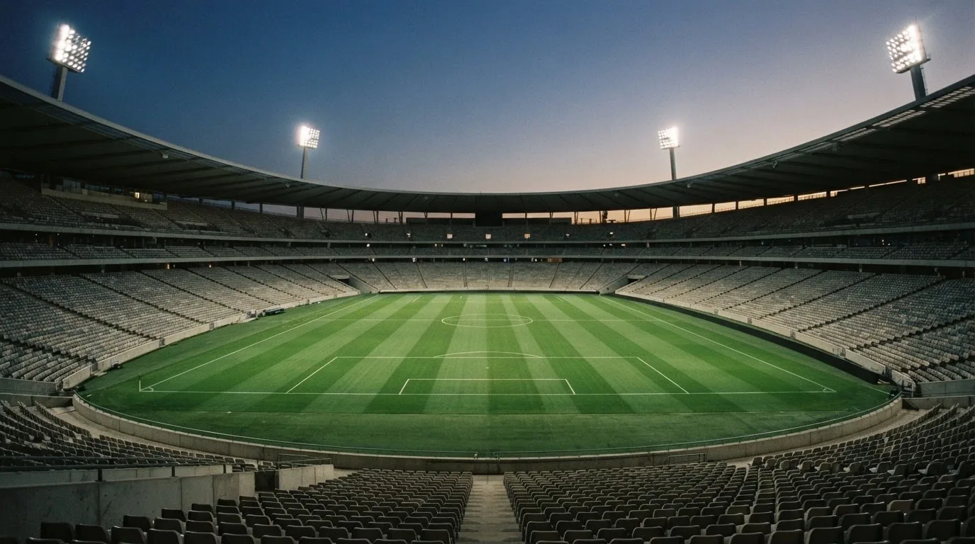 An empty football stadium with floodlight masts at dusk