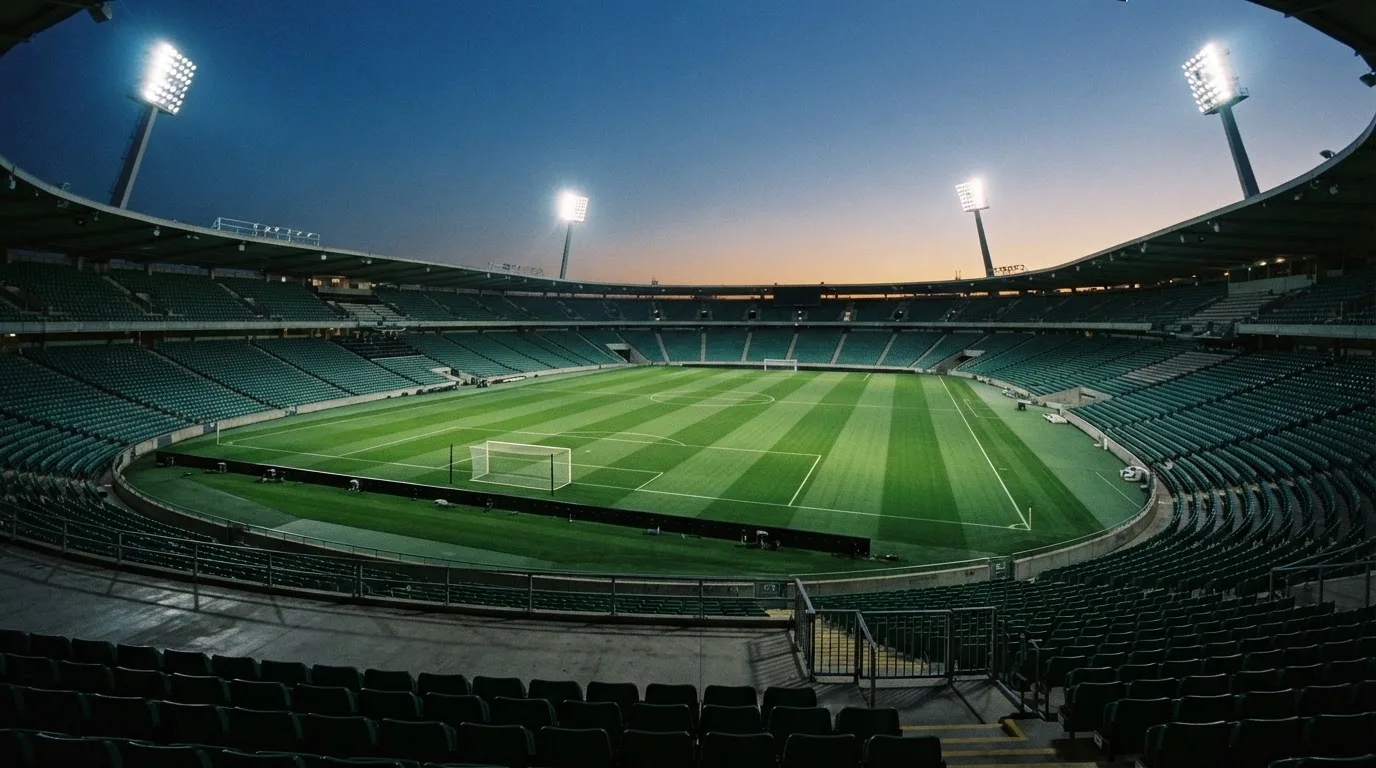 An empty football stadium with floodlight masts at dusk