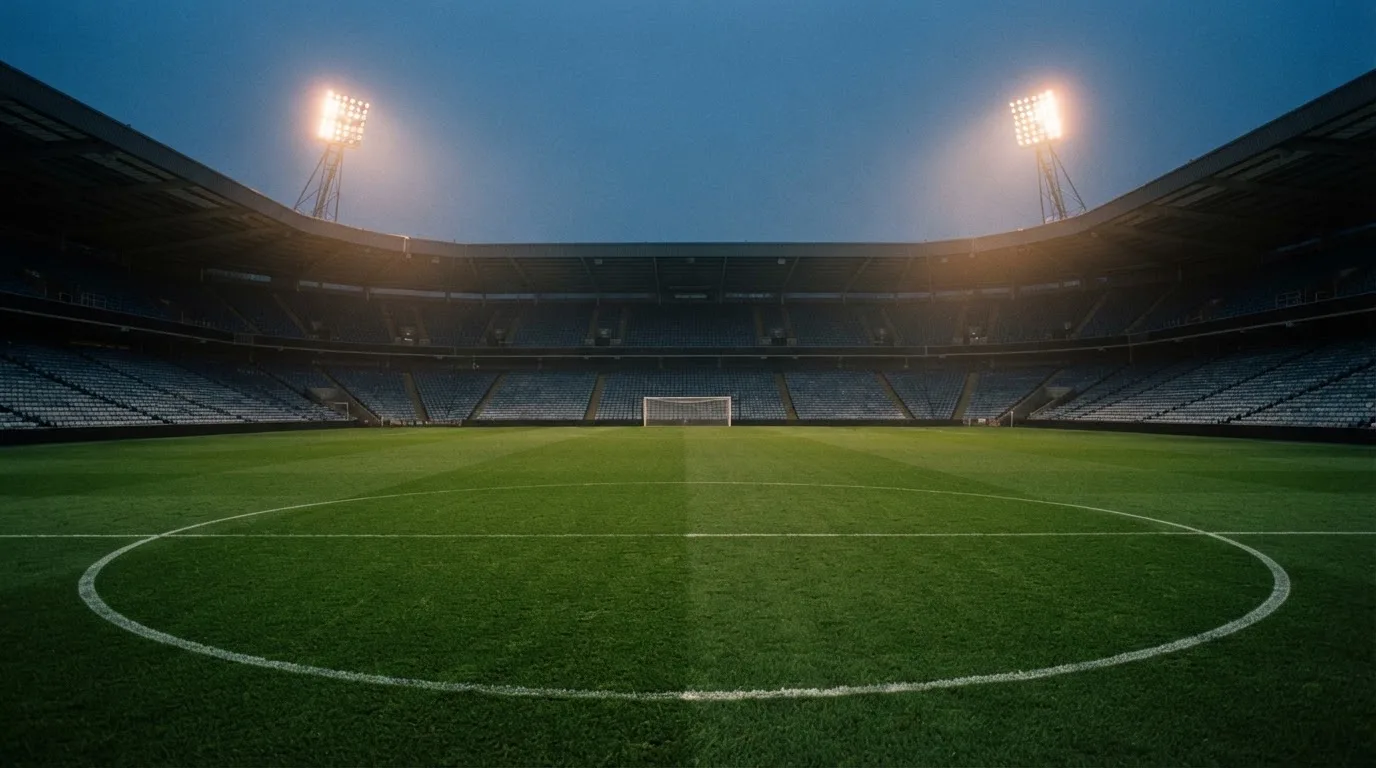 An empty football stadium with floodlight masts at dusk