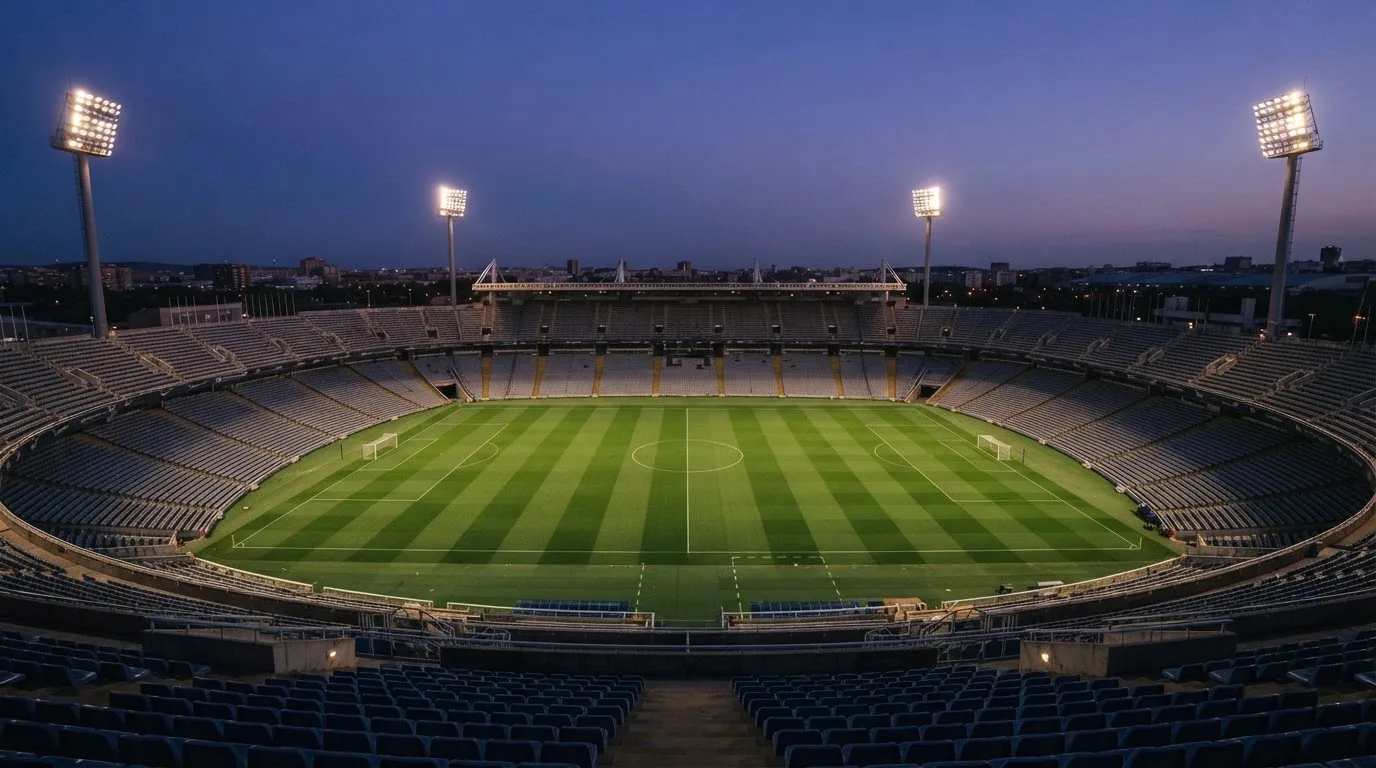 An empty football stadium with floodlight masts at dusk