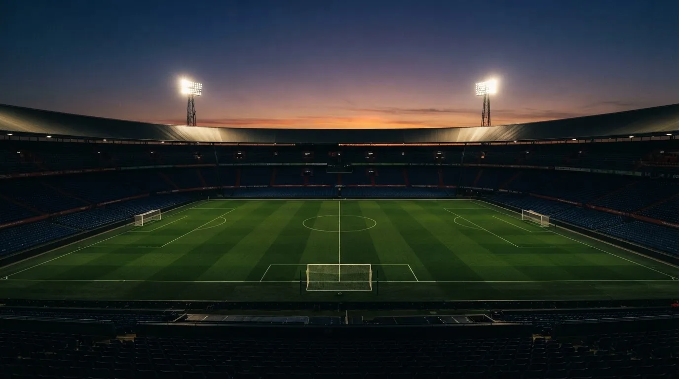 An empty football stadium with floodlight masts at dusk