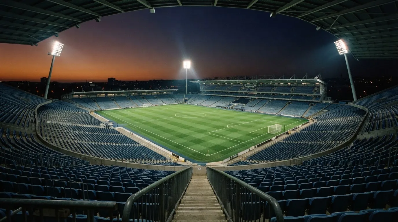 An empty football stadium with floodlight masts at dusk