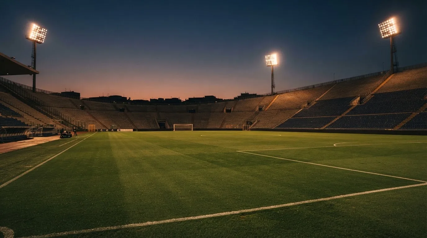 An empty football stadium with floodlight masts at dusk
