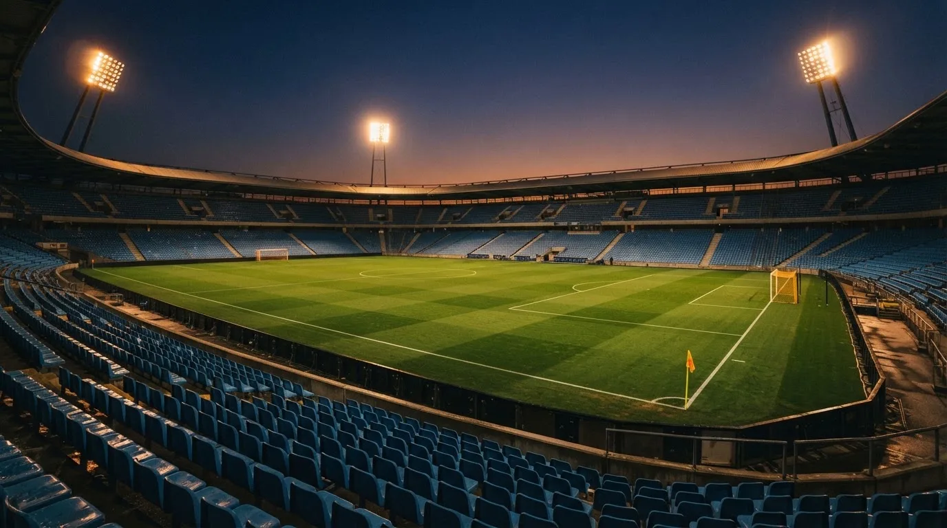 An empty football stadium with floodlight masts at dusk