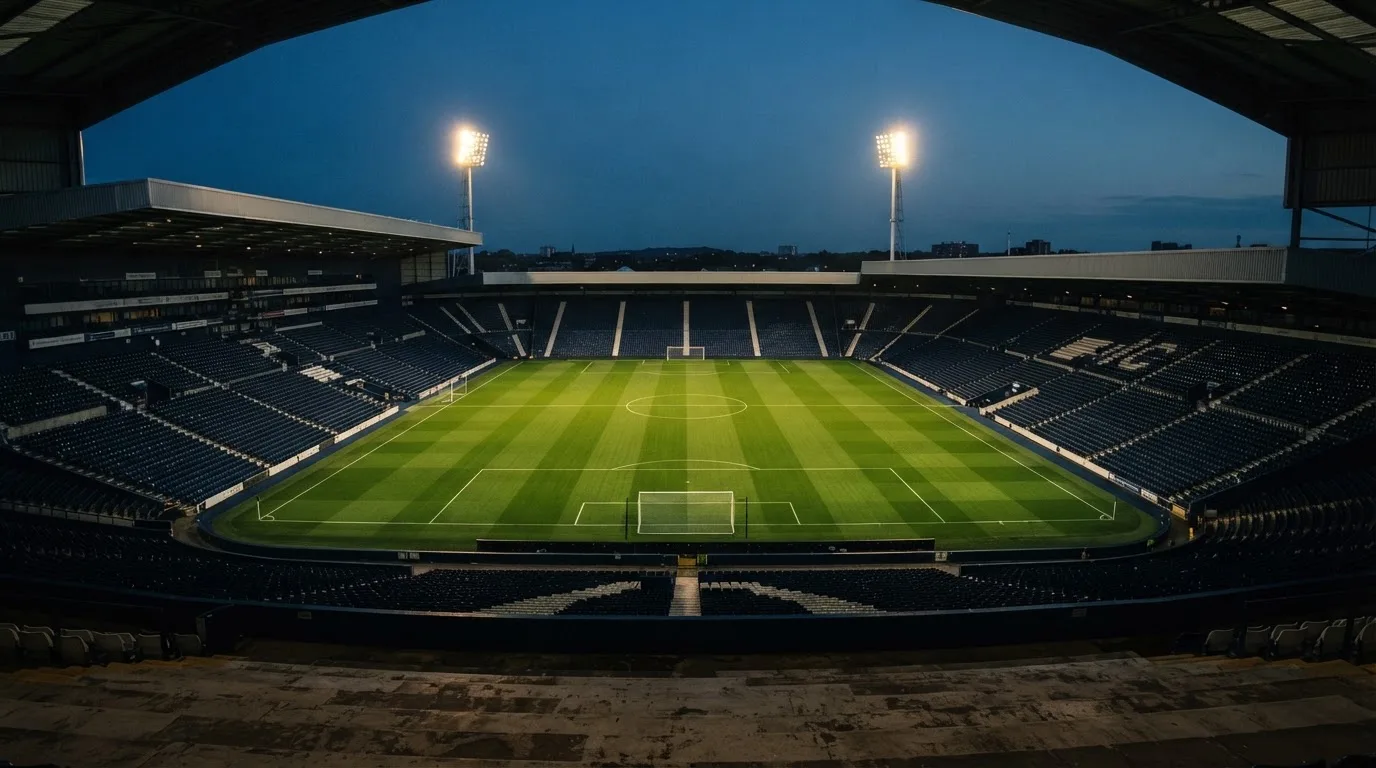 An empty football stadium with floodlight masts at dusk