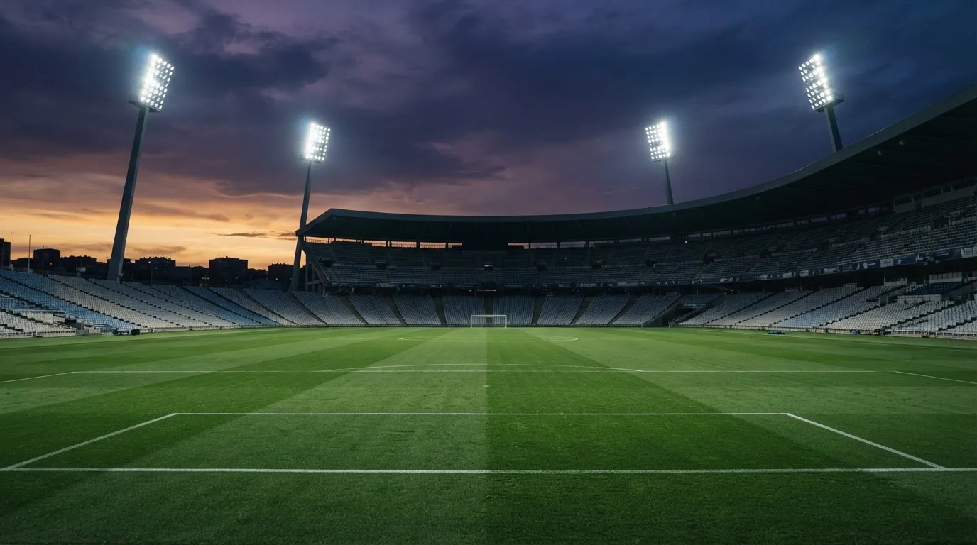 An empty football stadium with floodlight masts at dusk