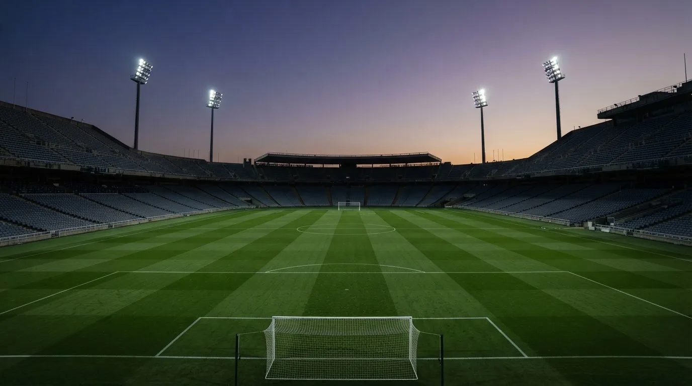 An empty football stadium with floodlight masts at dusk