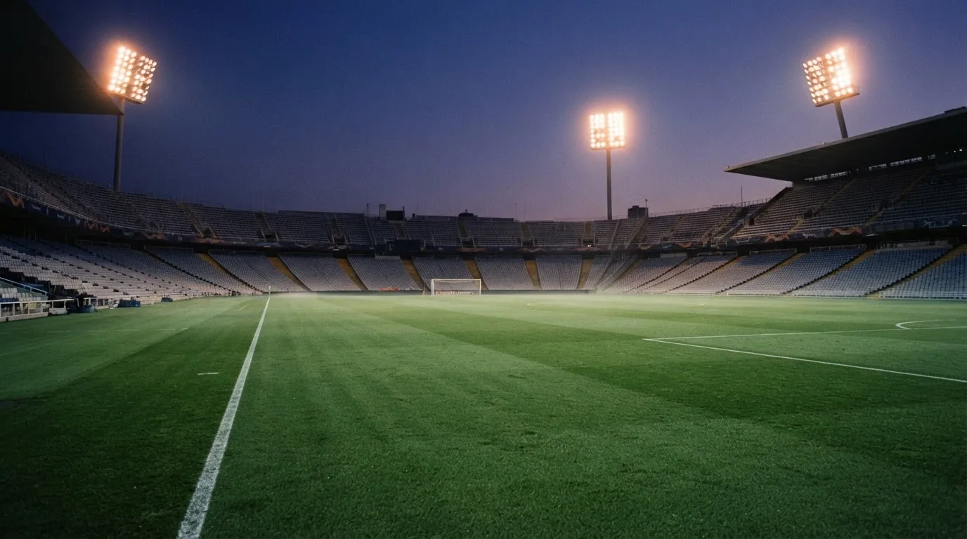 An empty football stadium with floodlight masts at dusk