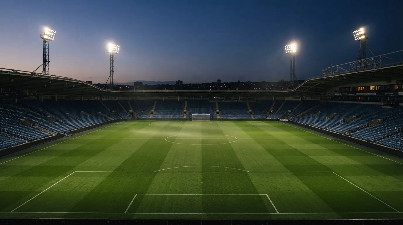 An empty football stadium with floodlight masts at dusk