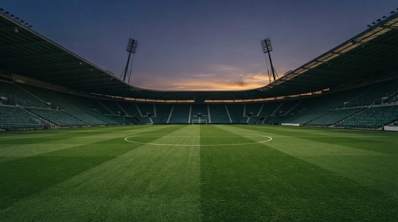 An empty football stadium with floodlight masts at dusk