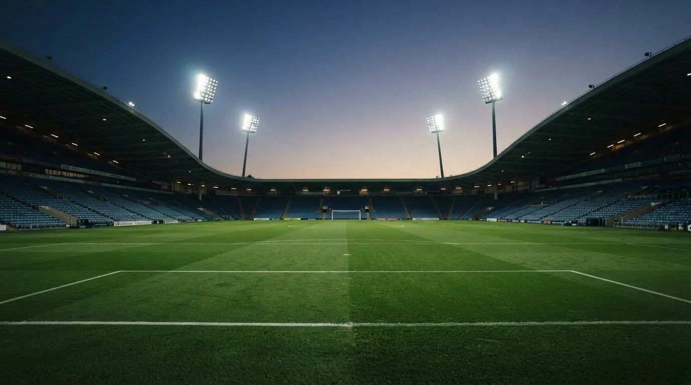 An empty football stadium with floodlight masts at dusk