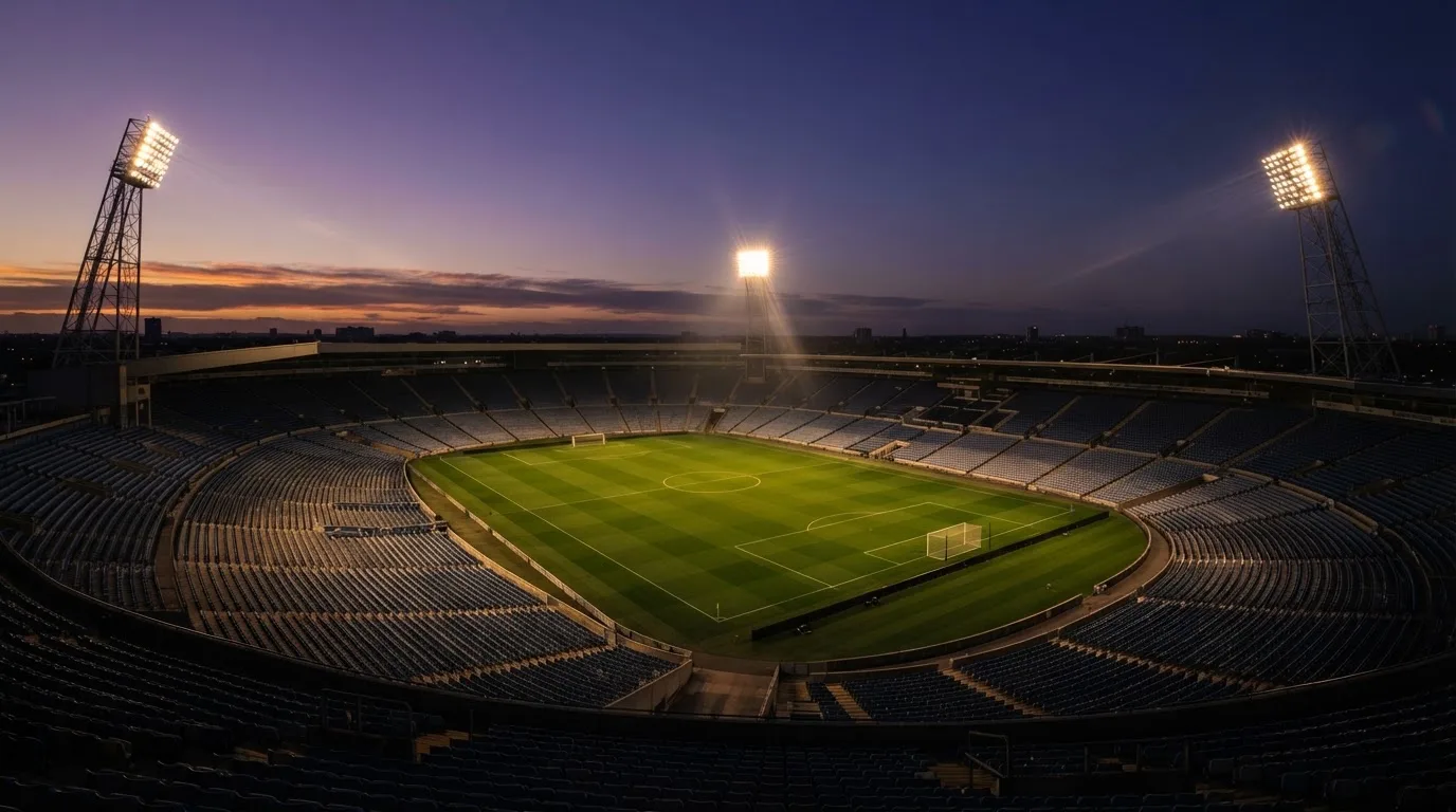 An empty football stadium with floodlight masts at dusk