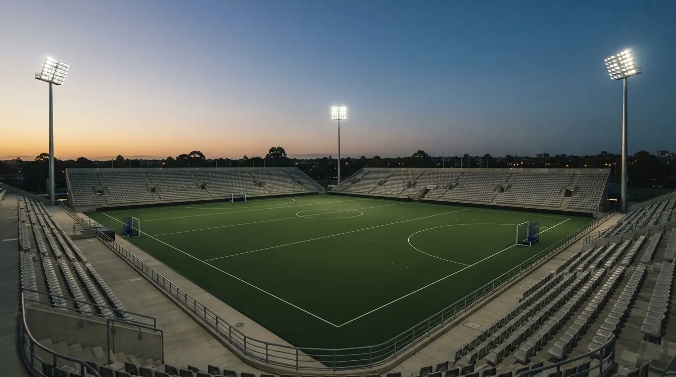 An empty football stadium with floodlight masts at dusk