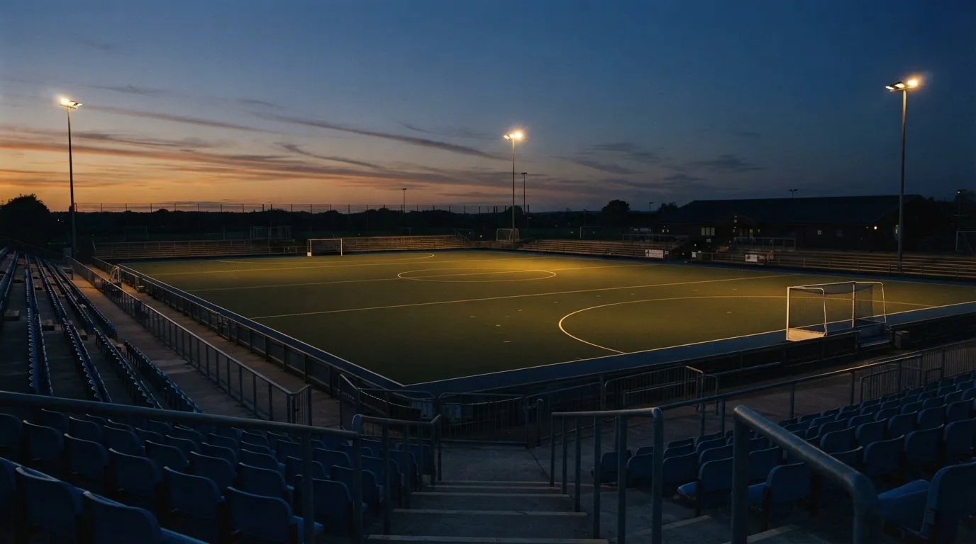 An empty football stadium with floodlight masts at dusk