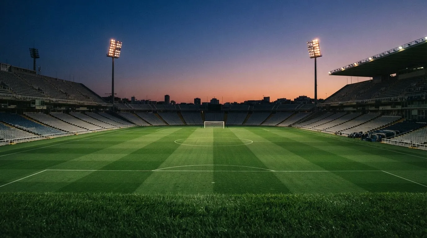 An empty football stadium with floodlight masts at dusk