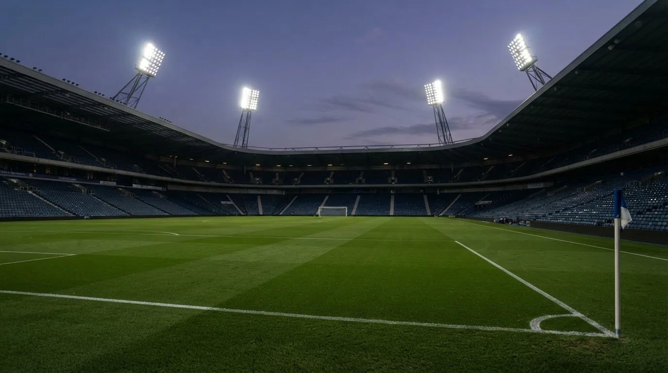 An empty football stadium with floodlight masts at dusk