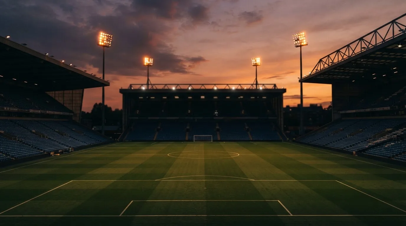 An empty football stadium with floodlight masts at dusk