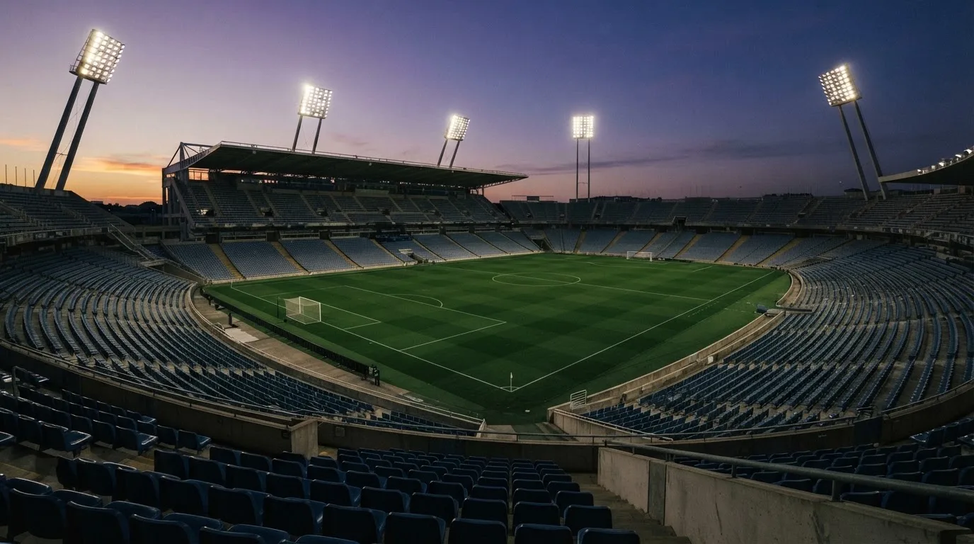 An empty football stadium with floodlight masts at dusk