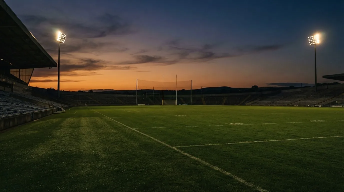 An empty football stadium with floodlight masts at dusk