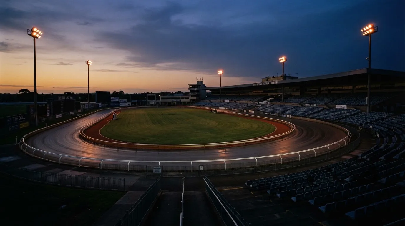 An empty football stadium with floodlight masts at dusk