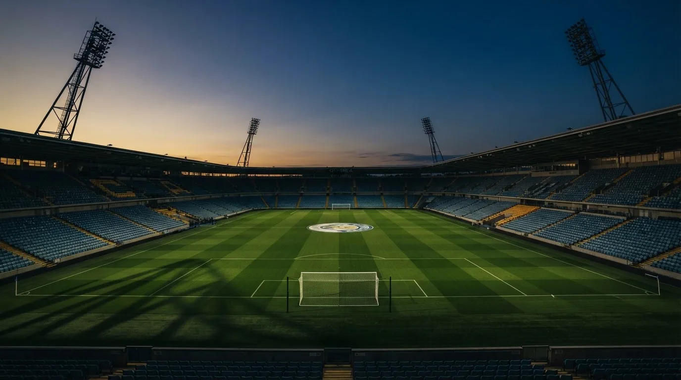 An empty football stadium with floodlight masts at dusk