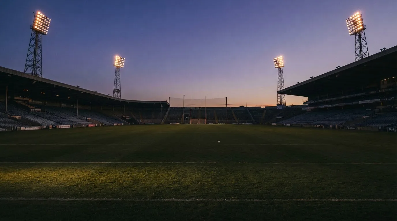 An empty football stadium with floodlight masts at dusk