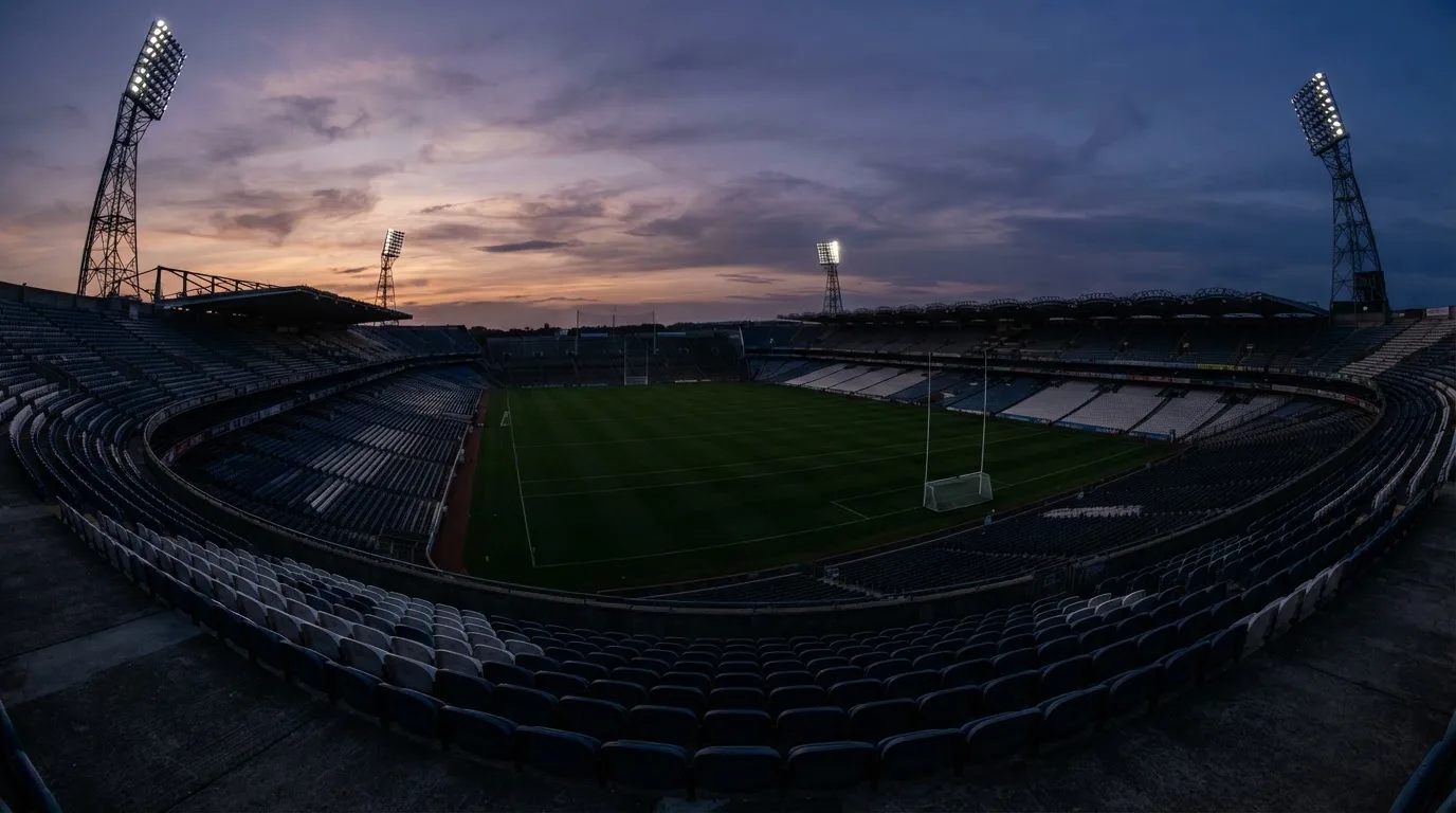 An empty football stadium with floodlight masts at dusk