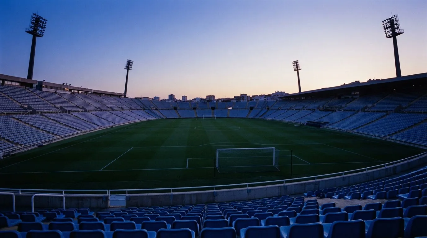 An empty football stadium with floodlight masts at dusk