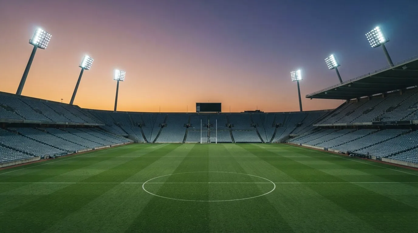 An empty football stadium with floodlight masts at dusk
