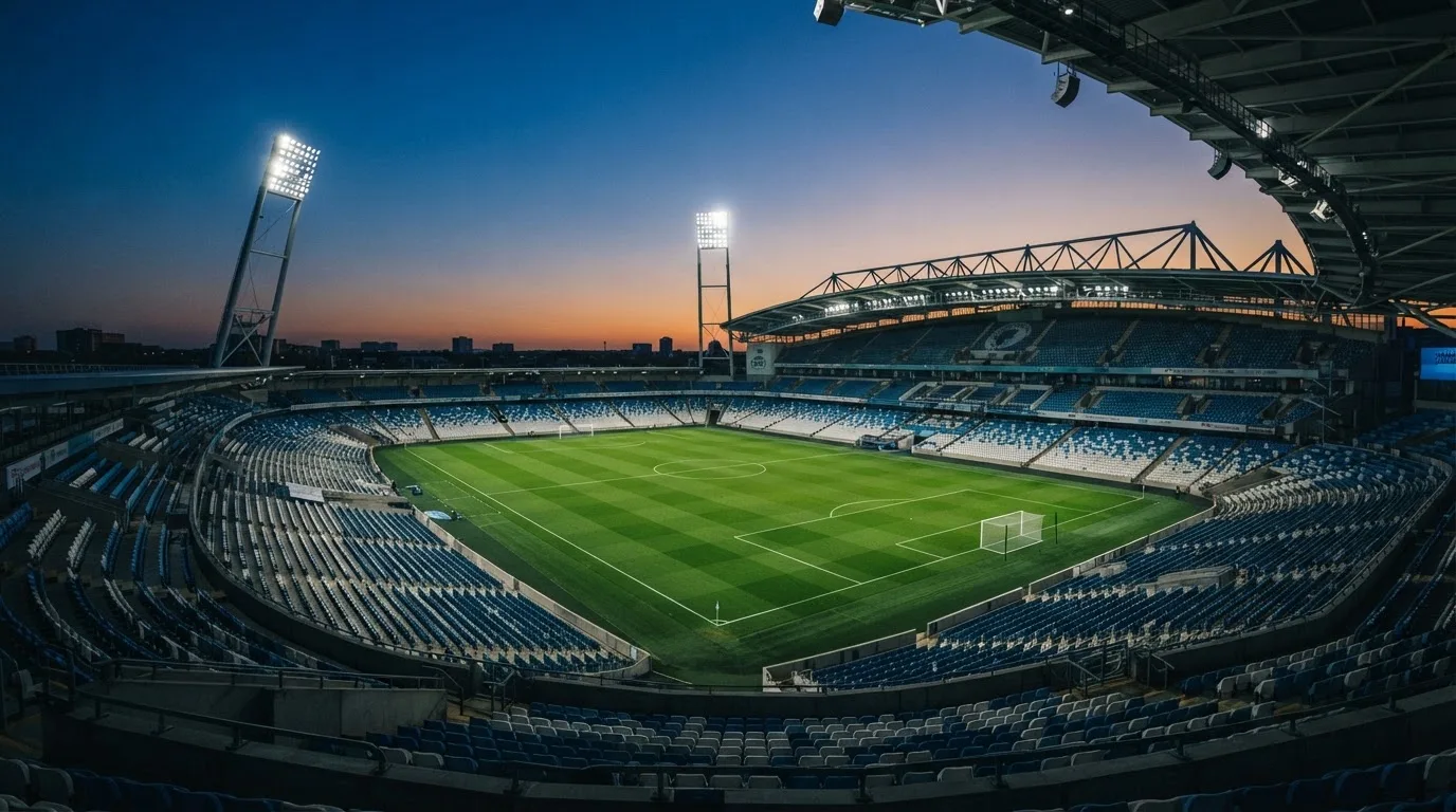 An empty football stadium with floodlight masts at dusk
