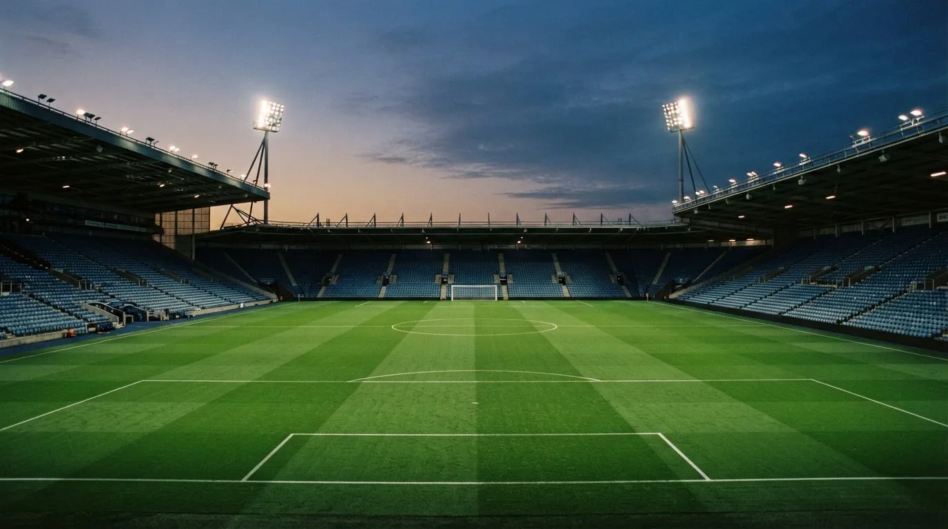 An empty football stadium with floodlight masts at dusk