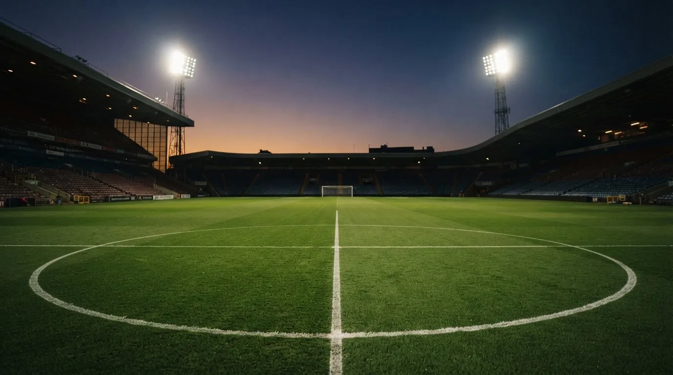 An empty football stadium with floodlight masts at dusk