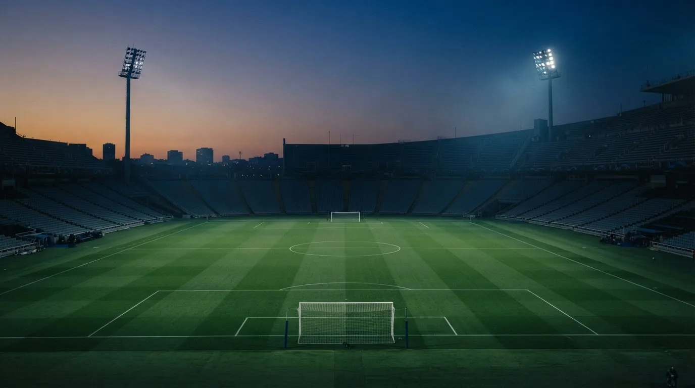 An empty football stadium with floodlight masts at dusk
