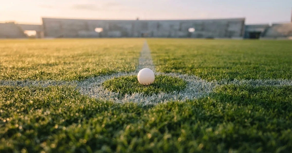 A ball on the centre spot of a grass pitch in morning light