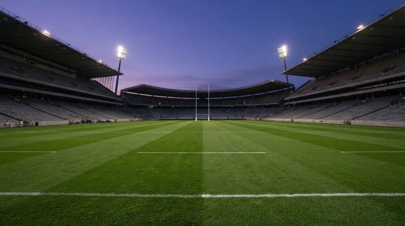 An empty football stadium with floodlight masts at dusk
