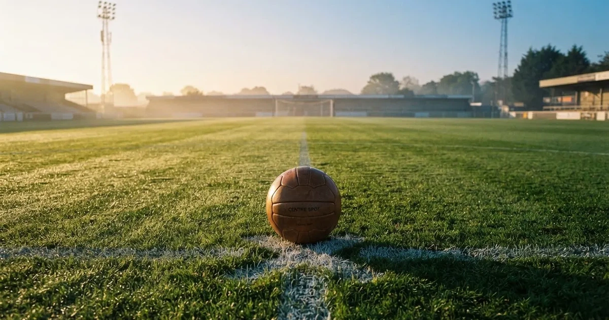 A ball on the centre spot of a grass pitch in morning light